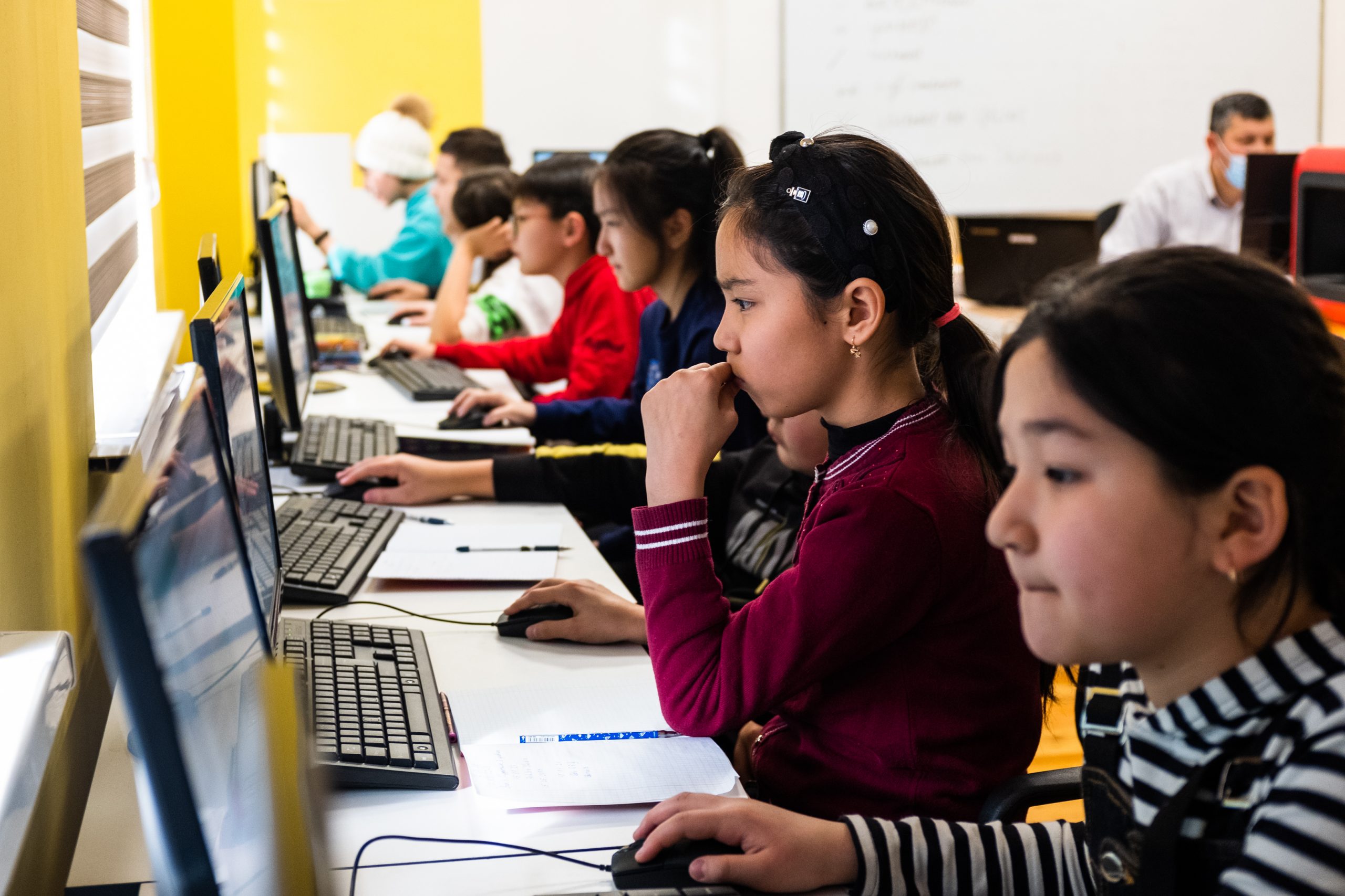 Young students using computers at a long table